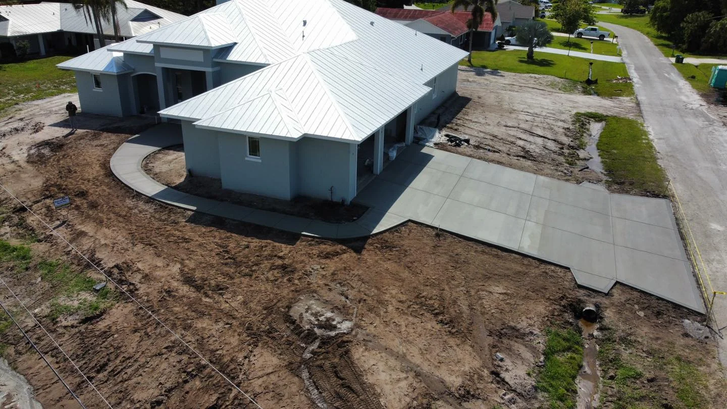 New construction home with metal roof and concrete driveway