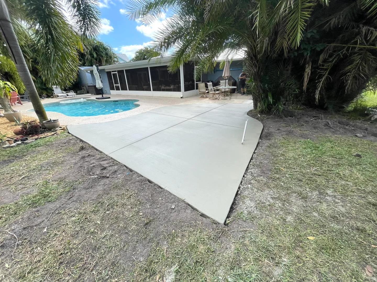 Newly poured concrete patio extension by pool